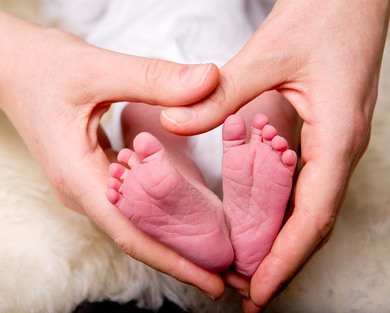 Region Örebro län. Omställning nära vård. Händer bildar ett hjärta runt en nyfödd bebis fötter.