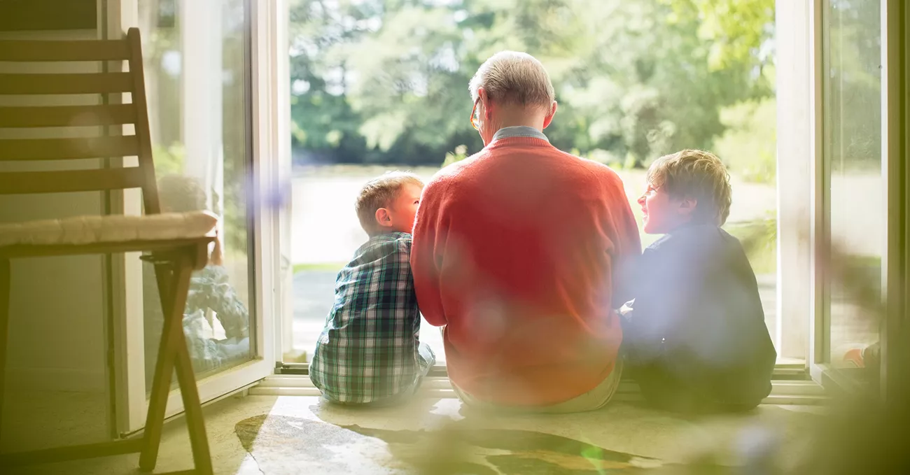 Grandfather and grandsons sitting in doorway